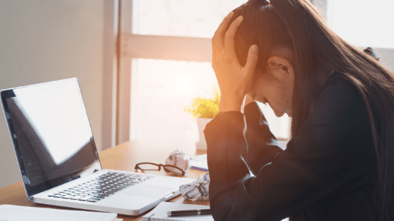 business woman at her desk with her head in her hands clearly stressed